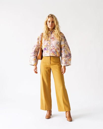 Giacca corta artigianale da donna con stampa artistica multicolore su fondo bianco, collo alto, maniche raglan e chiusura frontale con zip, indossata look1.