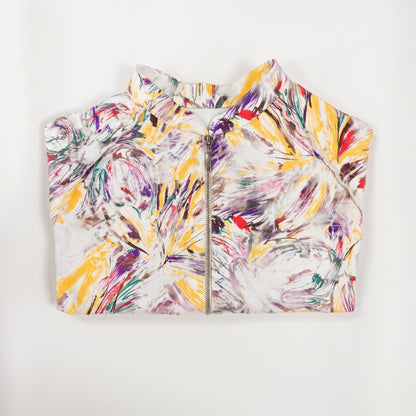 Giacca corta artigianale da donna con stampa artistica multicolore su fondo bianco, collo alto, maniche raglan e chiusura frontale con zip, vista piegata.