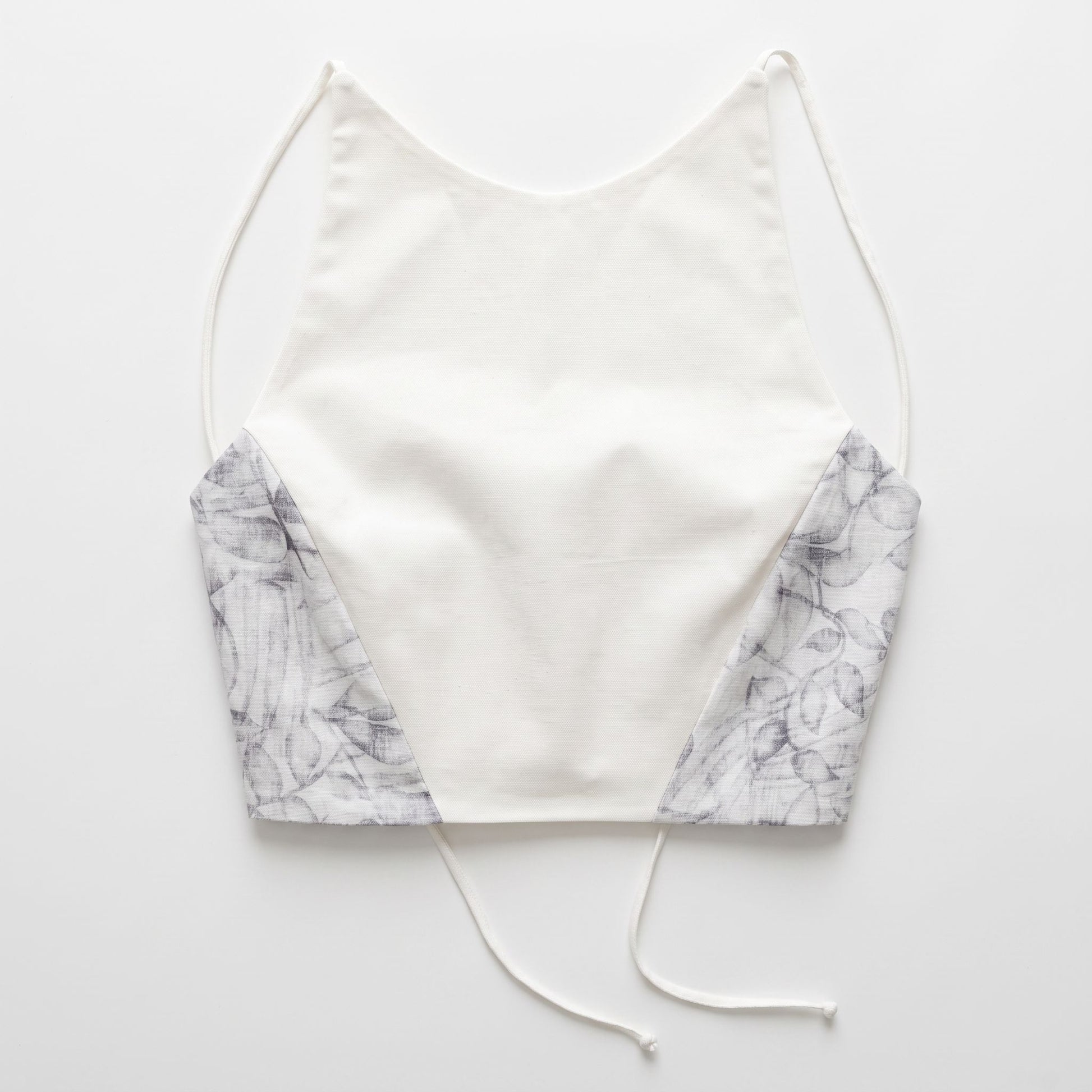 Top artigianale da donna in cotone bianco con inserti laterali a fantasia floreale e spalline sottili, vista frontale.