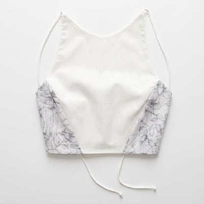 Top artigianale da donna in cotone bianco con inserti laterali a fantasia floreale e spalline sottili, vista frontale.