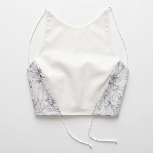 Top artigianale da donna in cotone bianco con inserti laterali a fantasia floreale e spalline sottili, vista frontale.