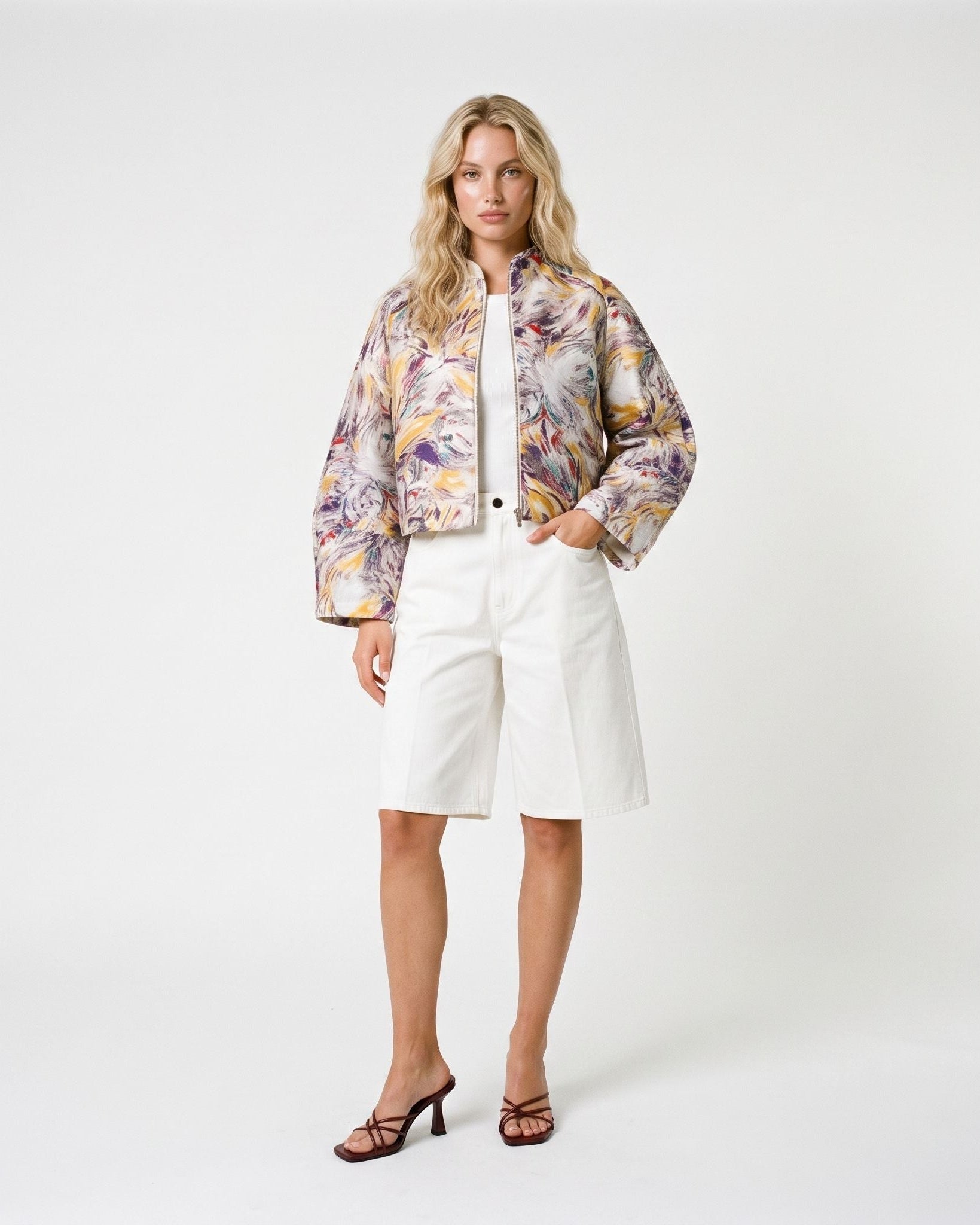 Modella indossa giacca crop a stampa floreale astratta abbinata a bermuda in denim bianco, look primaverile