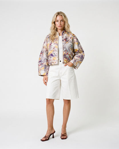 Modella indossa giacca crop a stampa floreale astratta abbinata a bermuda in denim bianco, look primaverile