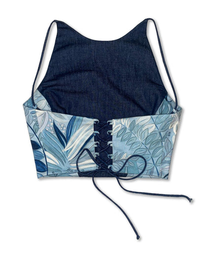 Vista posteriore del top artigianale in denim blu con inserti a fantasia foglie nei toni dell'azzurro e del bianco e chiusura regolabile con allacciatura sul retro.